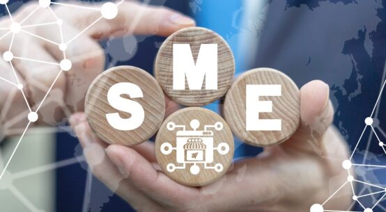 A man holding four round wooden blocks, in which the letters S , M, E are mentioned in white color, is a small mediumsized enterprises concept business.