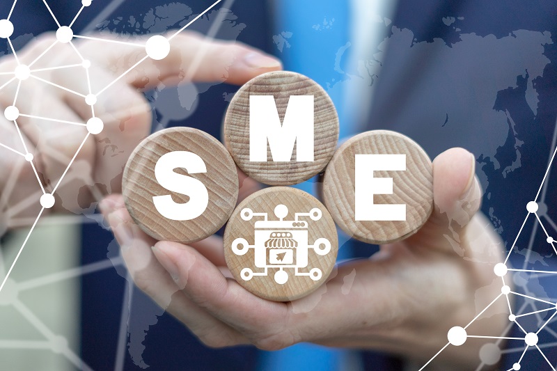 A man holding four round wooden blocks, in which the letters S , M, E are mentioned in white color, is a small mediumsized enterprises concept business.