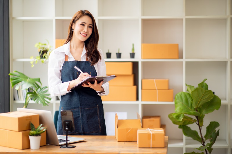 A woman entrepreneur is standing in the office holding an iPad and smiling at the customer